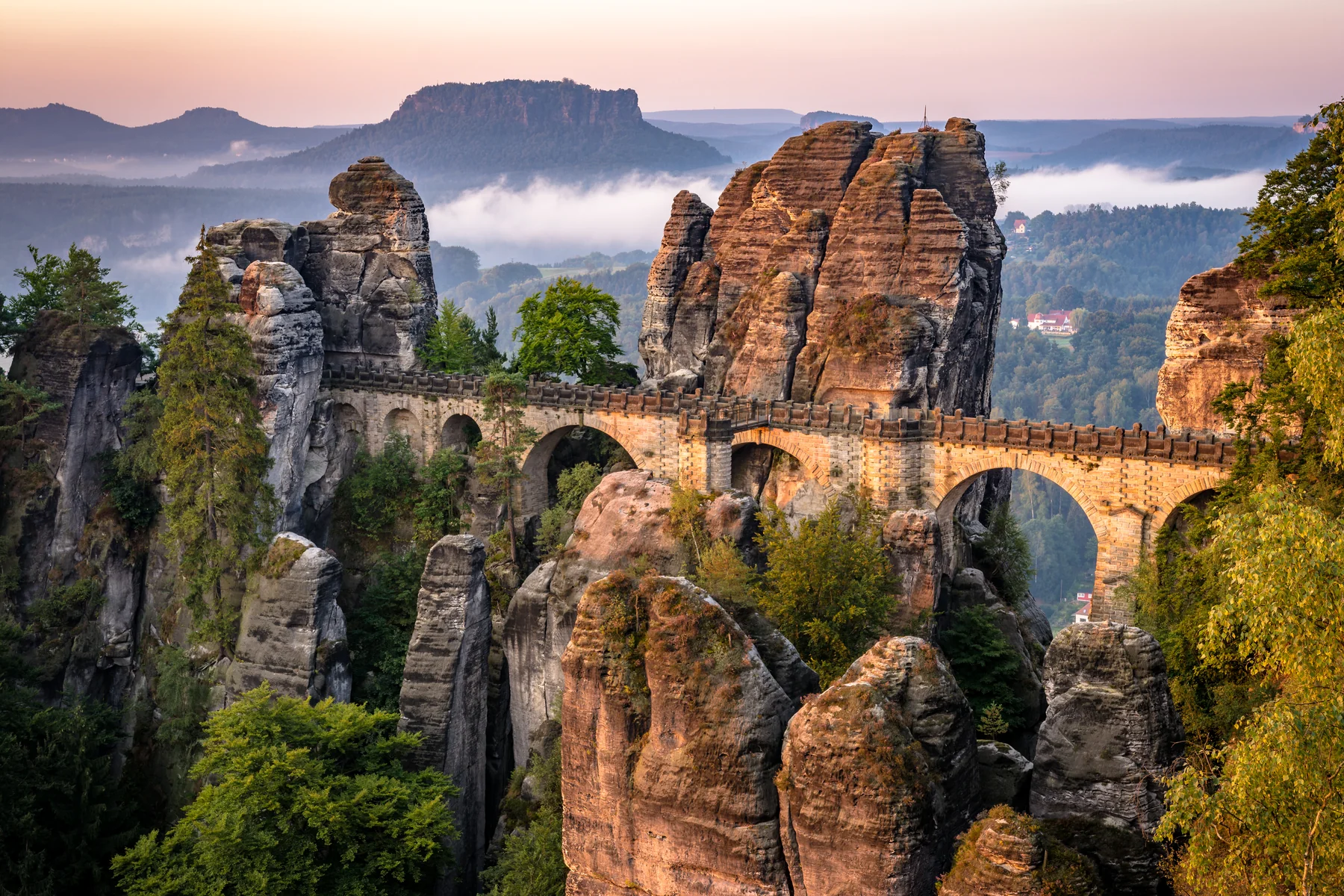 Die steinernen Bögen der Basteibrücke zwischen Sandsteintürmen am Morgen.