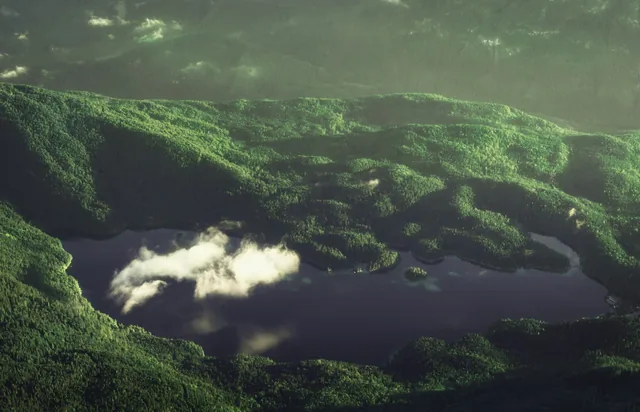 Blick auf den Eibsee mit kleinen Waldinseln und einer Nebelwolke.
